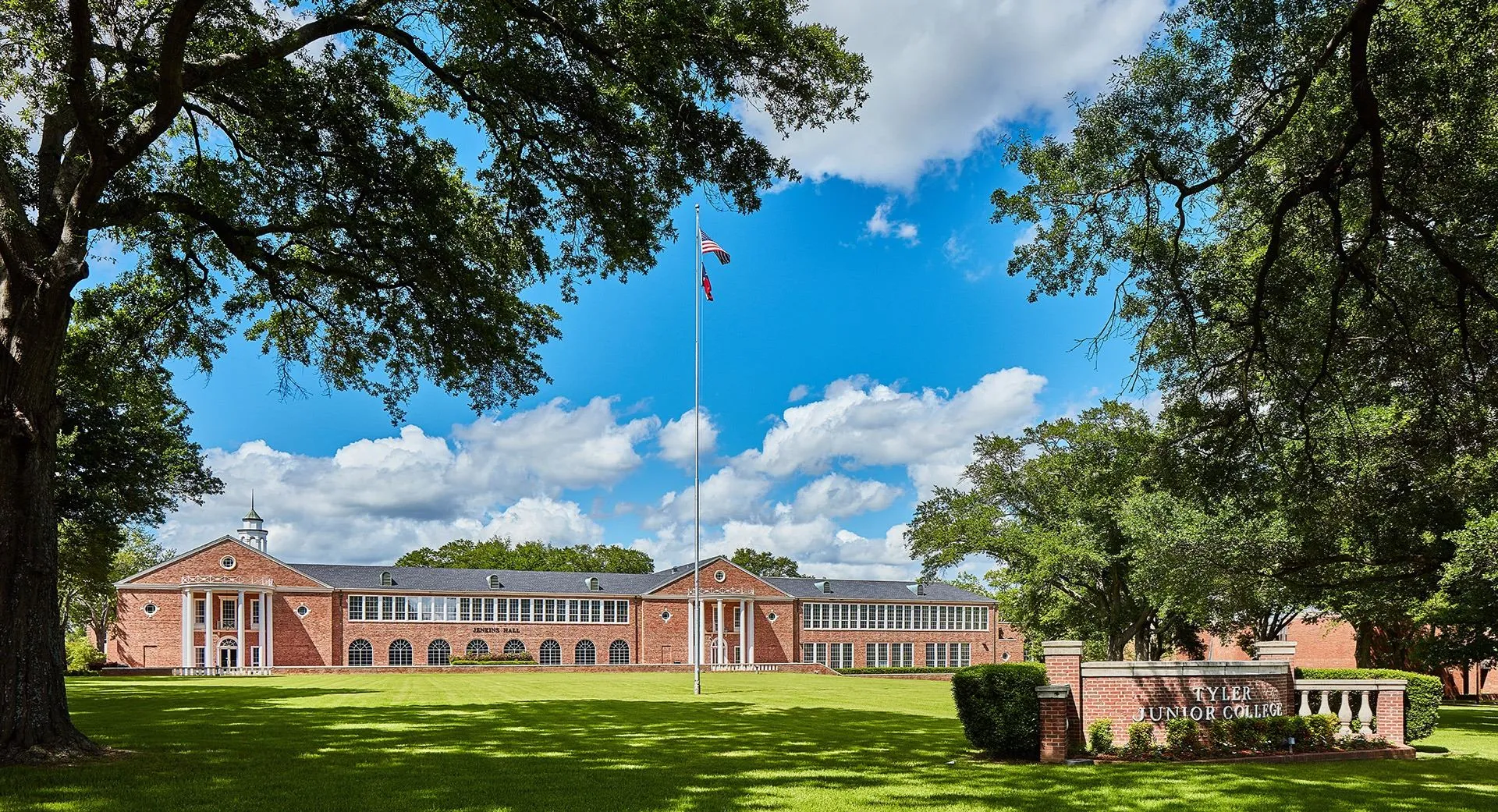 Wide lawn and circular driveway leading up to a two-story red-brick academic hall with tall white columns